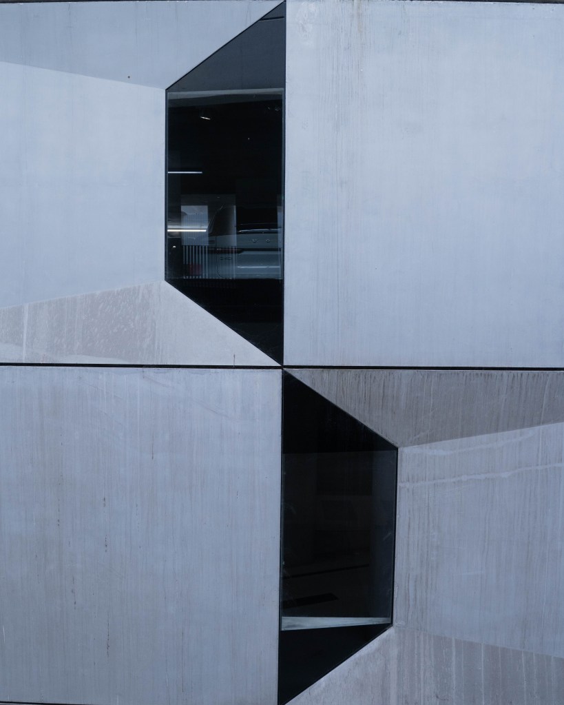 Close-up of a modern building exterior featuring geometric patterns and two rectangular windows.
