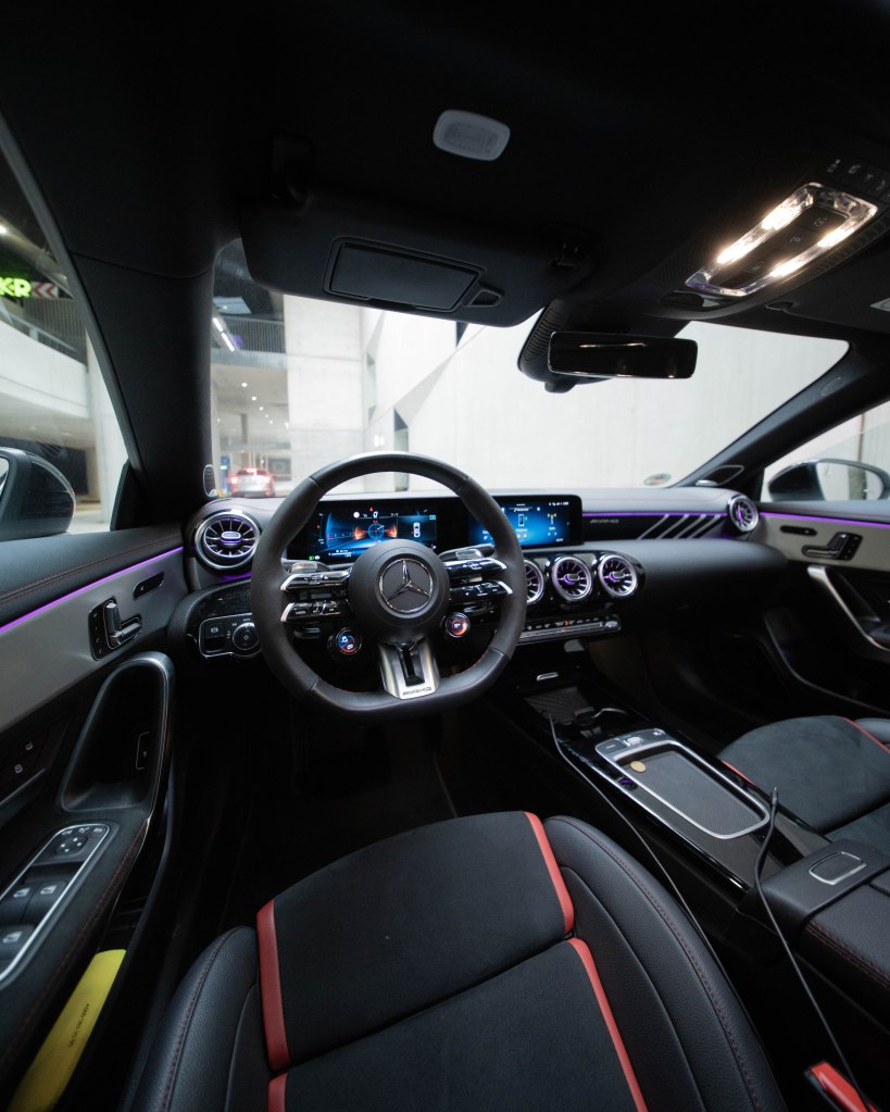 Interior of a sleek car featuring a modern dashboard, digital displays, a steering wheel with controls, and stylish seating.