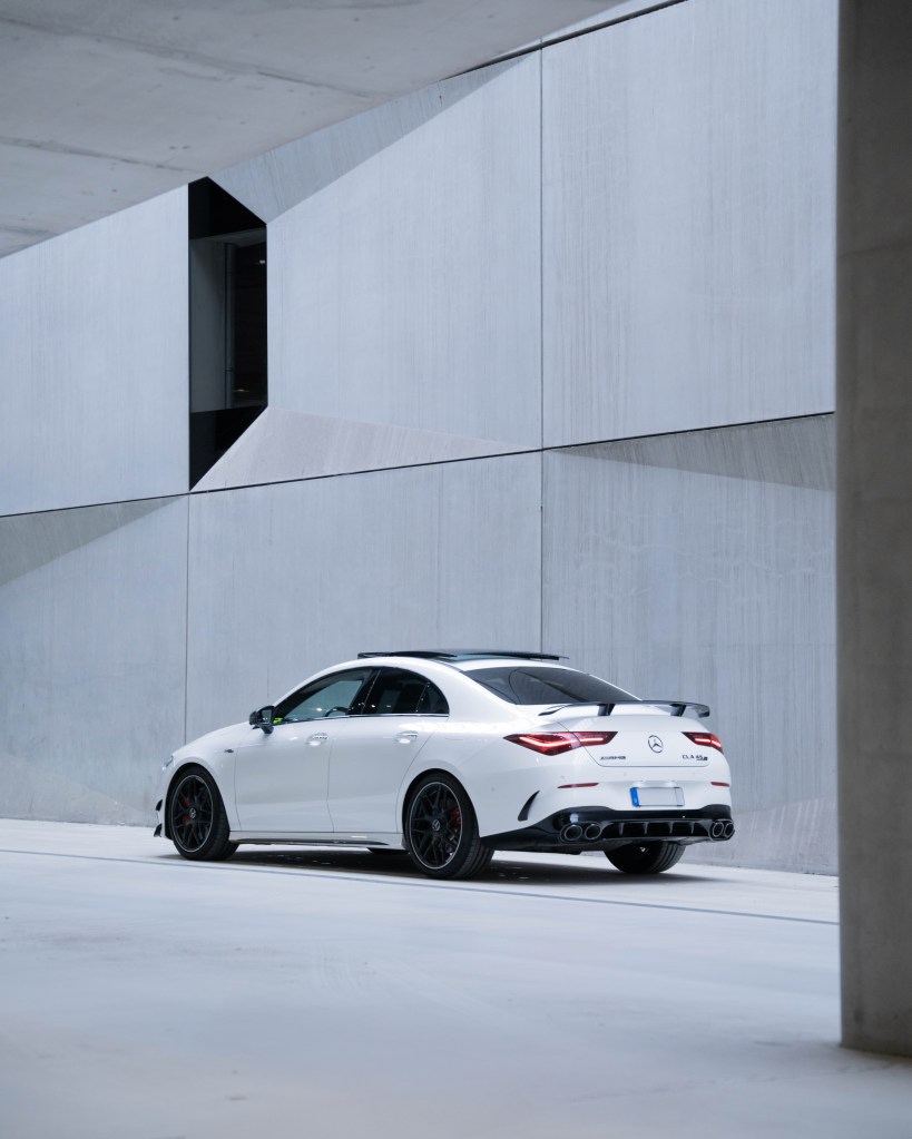 A sleek white Mercedes-Benz sports car parked in a modern concrete architectural setting.