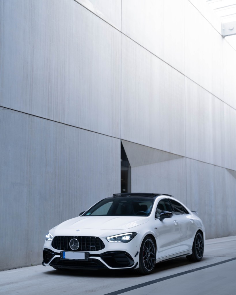 A sleek white Mercedes-Benz parked in a modern, minimalist setting with smooth concrete walls.